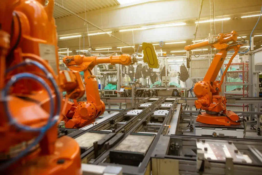 Linia produkcyjna z pomarańczowymi ramionami robotów w fabryce